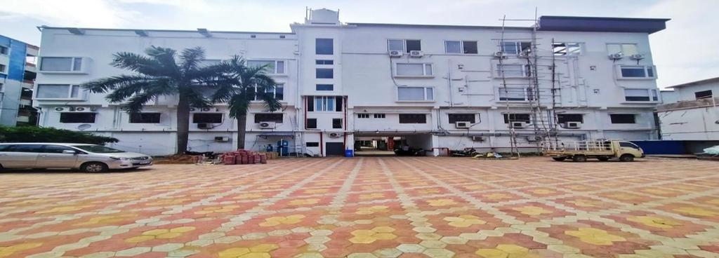 a large white building with cars parked in a parking lot at Hotel Heritage Inn in Balasore
