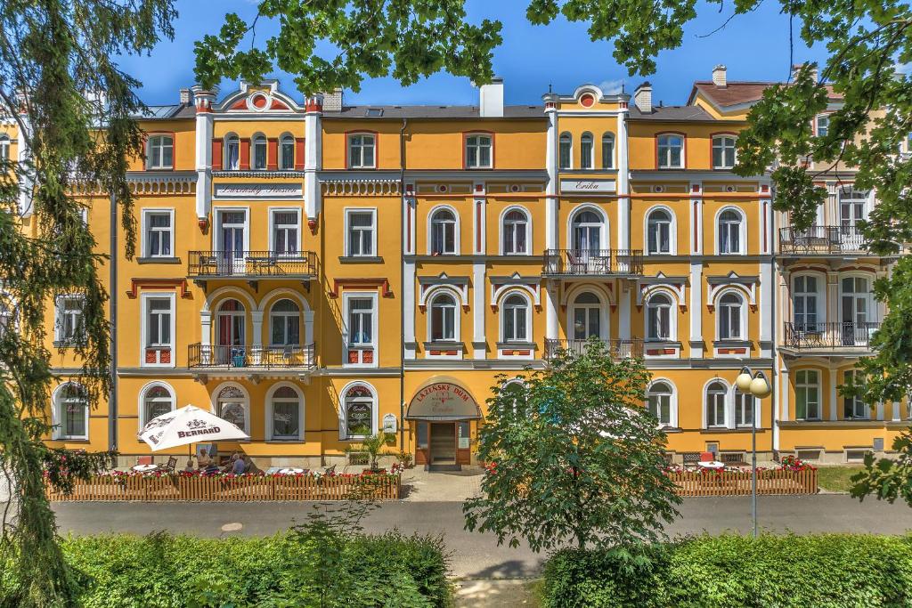 a large yellow building with tables in front of it at Lázeňský dům Erika in Františkovy Lázně