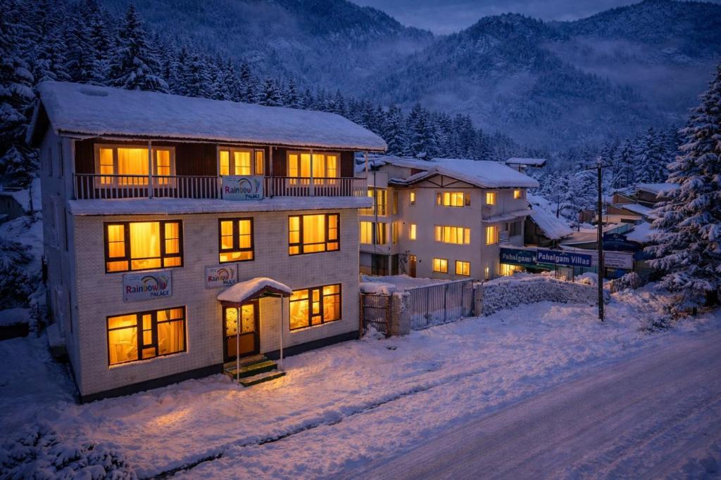 a house with its lights on in the snow at Rainbow Palace Pahalgam in Pahalgām