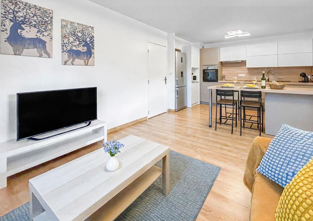 a living room with a flat screen tv and a kitchen at La forêt, T3 Design, Parking, Face à la Gare in Grenoble