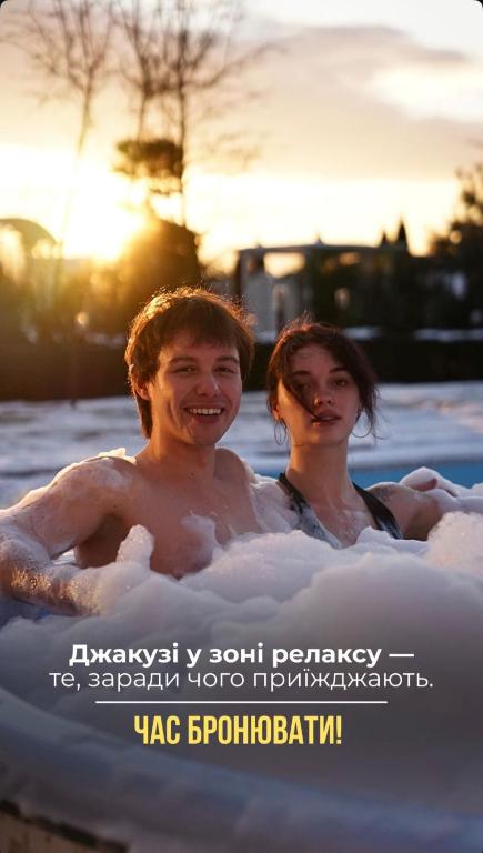 two people are in the water in a swimming pool at Кузня міні-готель СПА ЗОНА та сніданки входять у вартість in Mateyevtsy