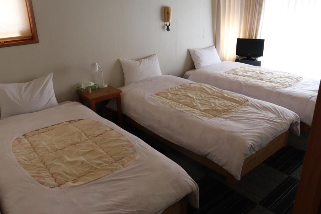a hotel room with two beds and a window at ペンション愛宕道 in Kyoto