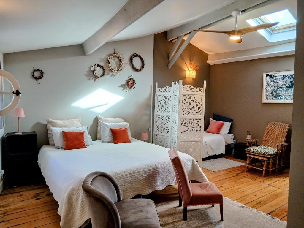 a bedroom with a large white bed and a chair at La maison botanique in Castillon-la-Bataille