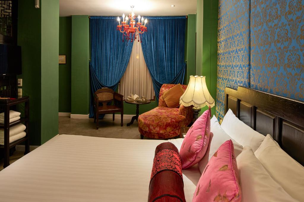 A close bedroom view showing a decorated bed, draped window and chaise longue.
