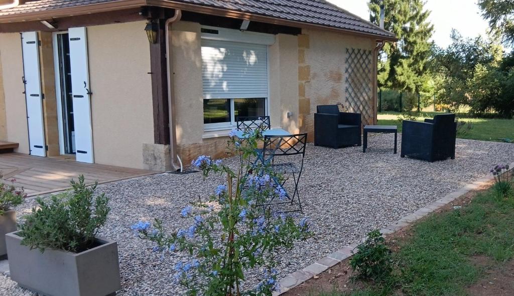 a patio with a table and chairs in front of a house at Studio bois du bournat piscine et tranquilité in Saint-Avit-Sénieur