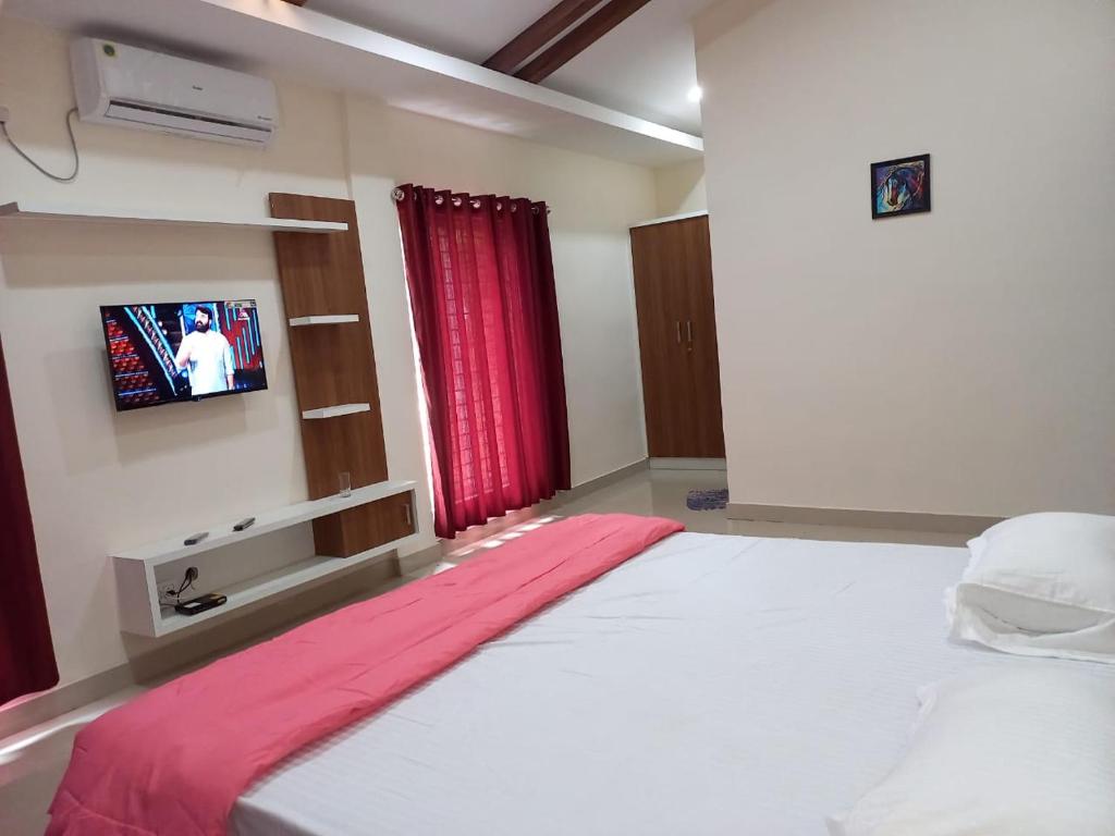 a bedroom with a bed with a tv on the wall at WHITE FLOWER mountain resort in Perintalmanna