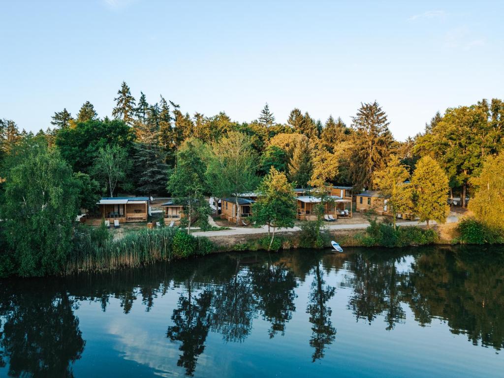 a group of houses on the shore of a lake at Camping Etang de Sologne in Nouan-le-Fuzelier