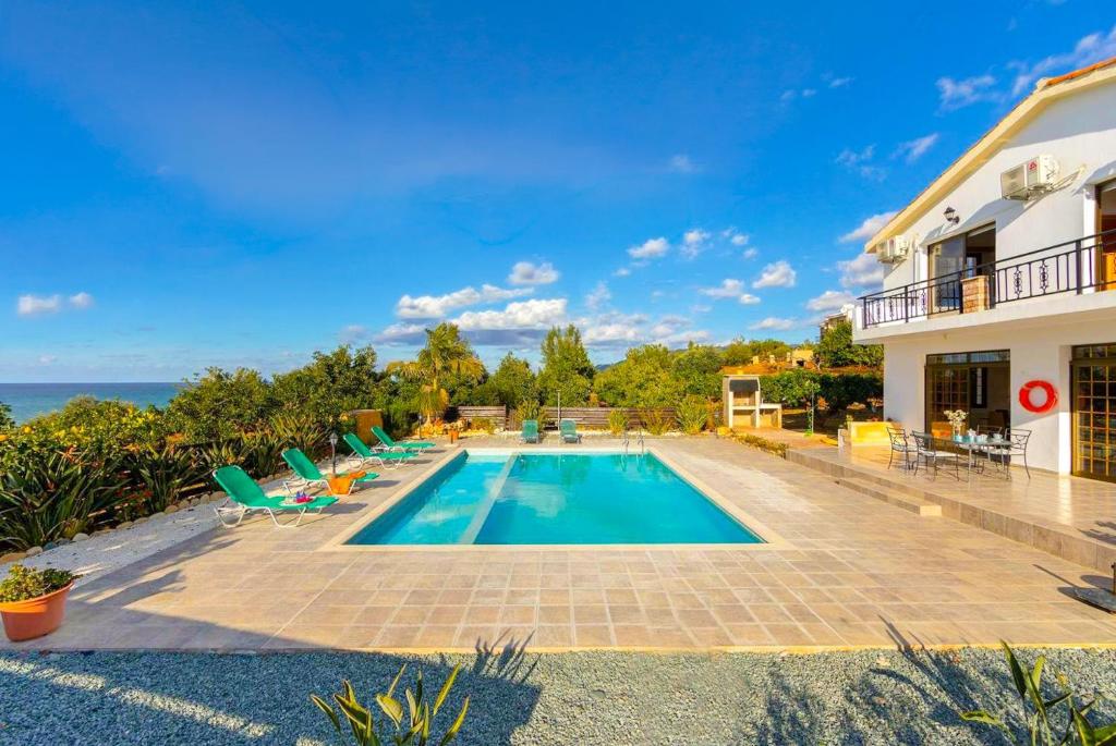 a swimming pool in front of a house at Villa Adonis Large Private Pool Walk to Beach in Argaka