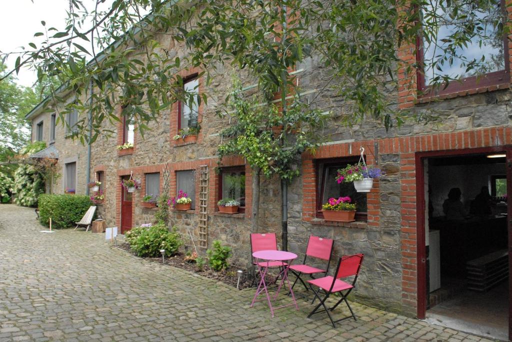 a group of pink chairs and a table outside a building at Ferme du Banoyard in Theux