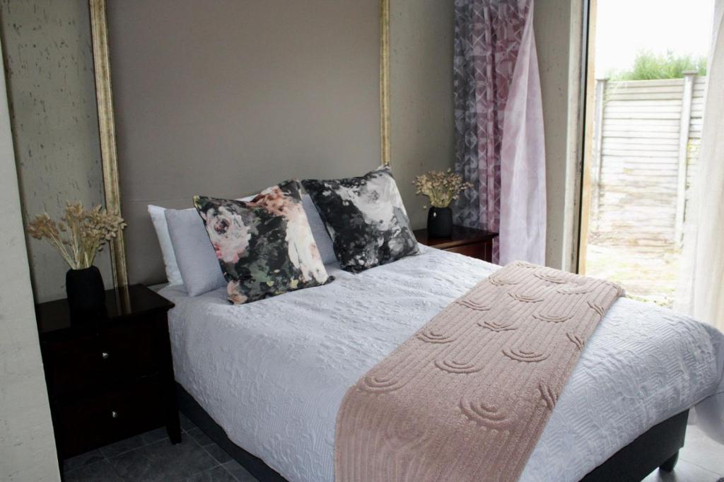 a bedroom with a bed with pillows and a window at Saints boutique lodge in Bloemfontein