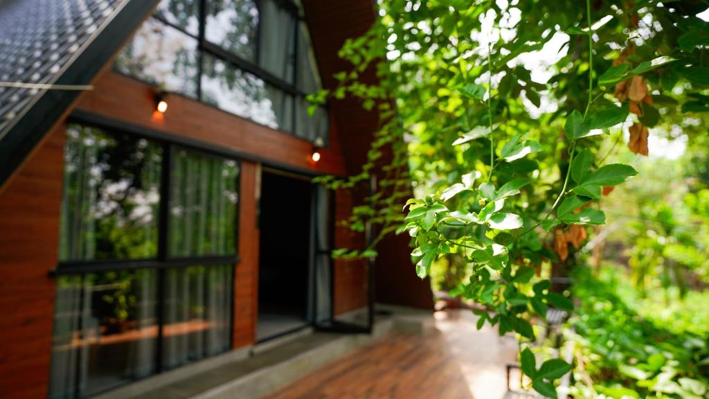 a house with glass windows and a wooden floor at Lostcabins in Vallikavungal