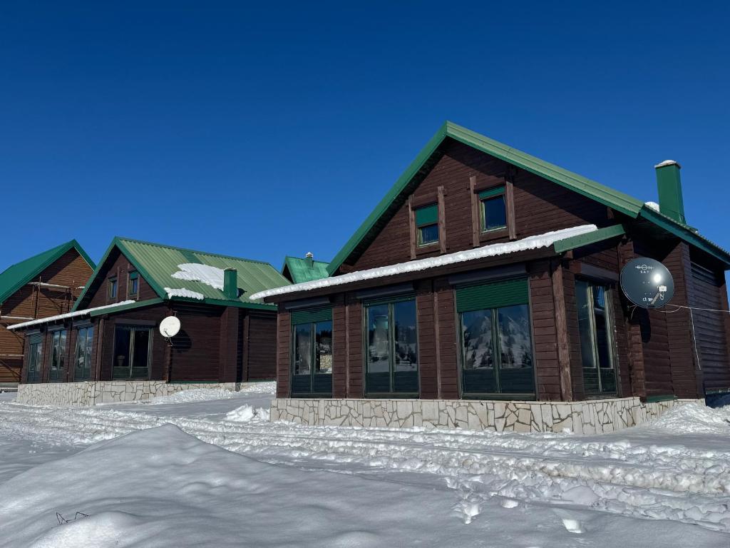 a building with snow on the ground in front of it at Mountain houses Milovanovic in Žabljak
