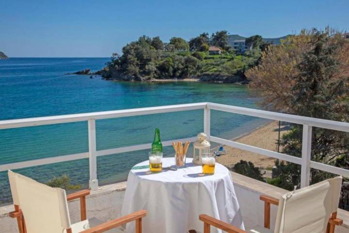 a table with a bottle and two glasses on a balcony at ENDLESS BLUE WAVE in Paleo Tsifliki