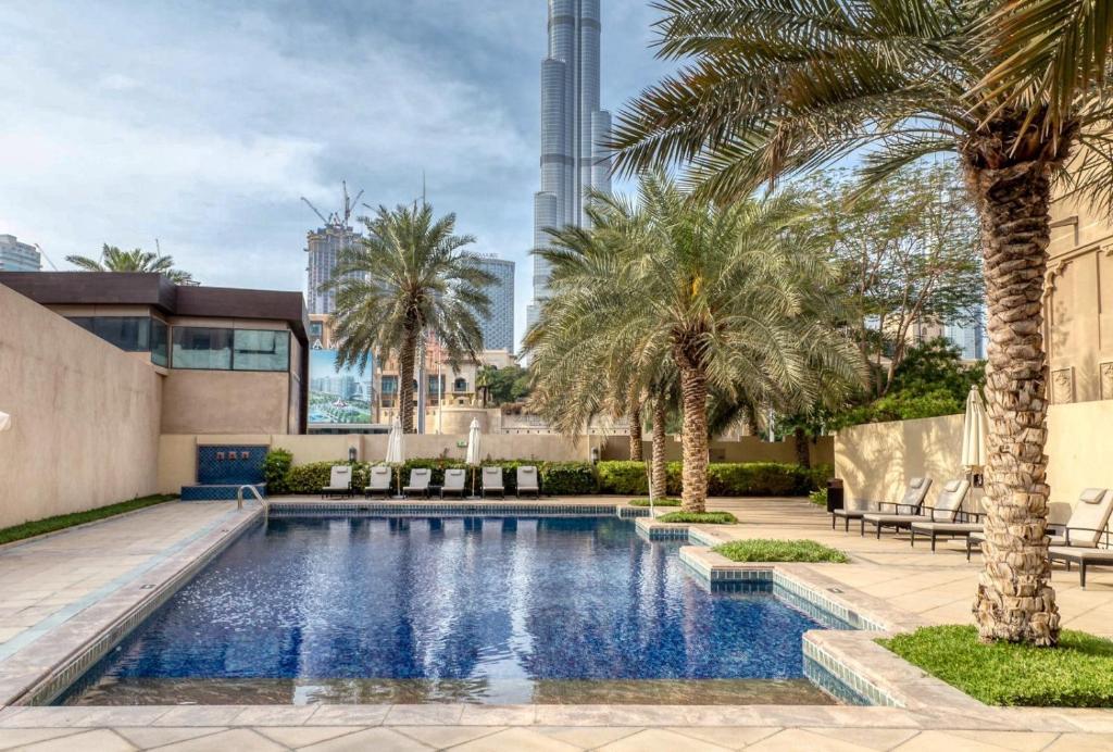 a swimming pool with palm trees and a building at GuestReady - 1BR | Private Garden - Burj Khalifa in Dubai