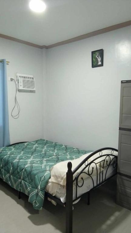 a bedroom with a bed with a green comforter at RMBC beds and breakfast in Badian