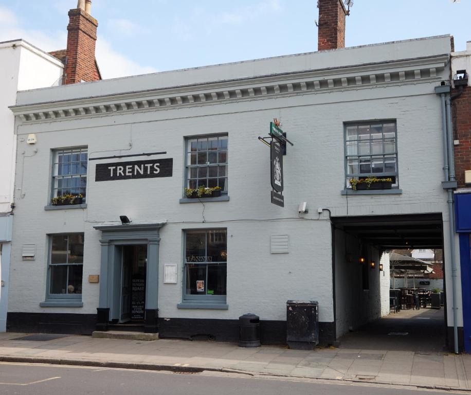 a white building with a sign that reads treats at Trents by Greene King Inns in Chichester