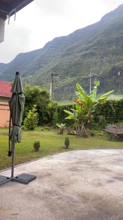 an umbrella on a stand in front of a mountain at Le repaire de la mare in Salazie