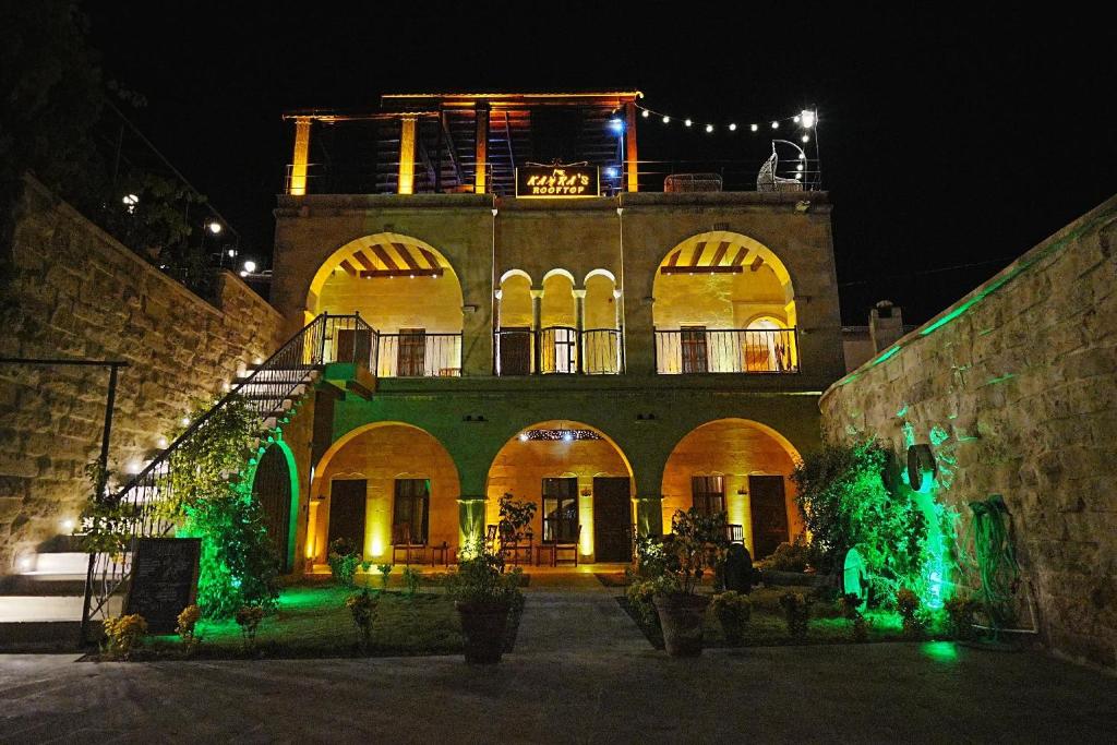 an old building with a large building at night at Kayra Cave Suites in Göreme