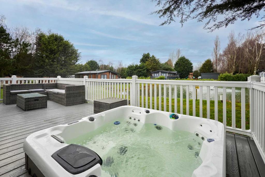 a hot tub on a deck with a fence at Sutton Lodge with Hot Tub in York
