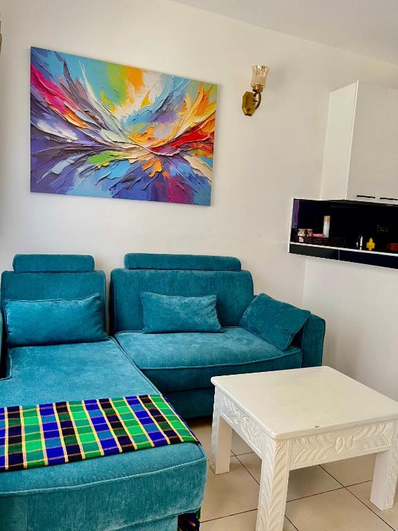 a living room with blue couches and a painting at Magenta Apartment in Diani Beach