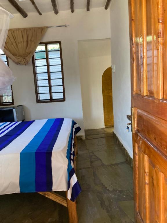 a bedroom with a bed and a wooden door at Petcat Cottage in Diani Beach
