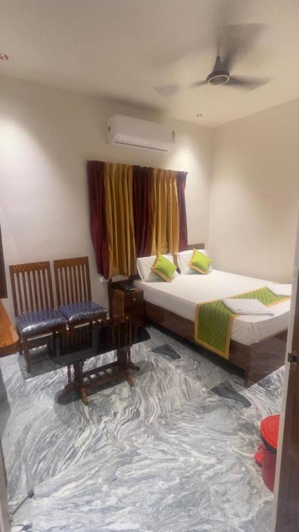 a room with two beds and a chair in it at Swapnainn in Ongole