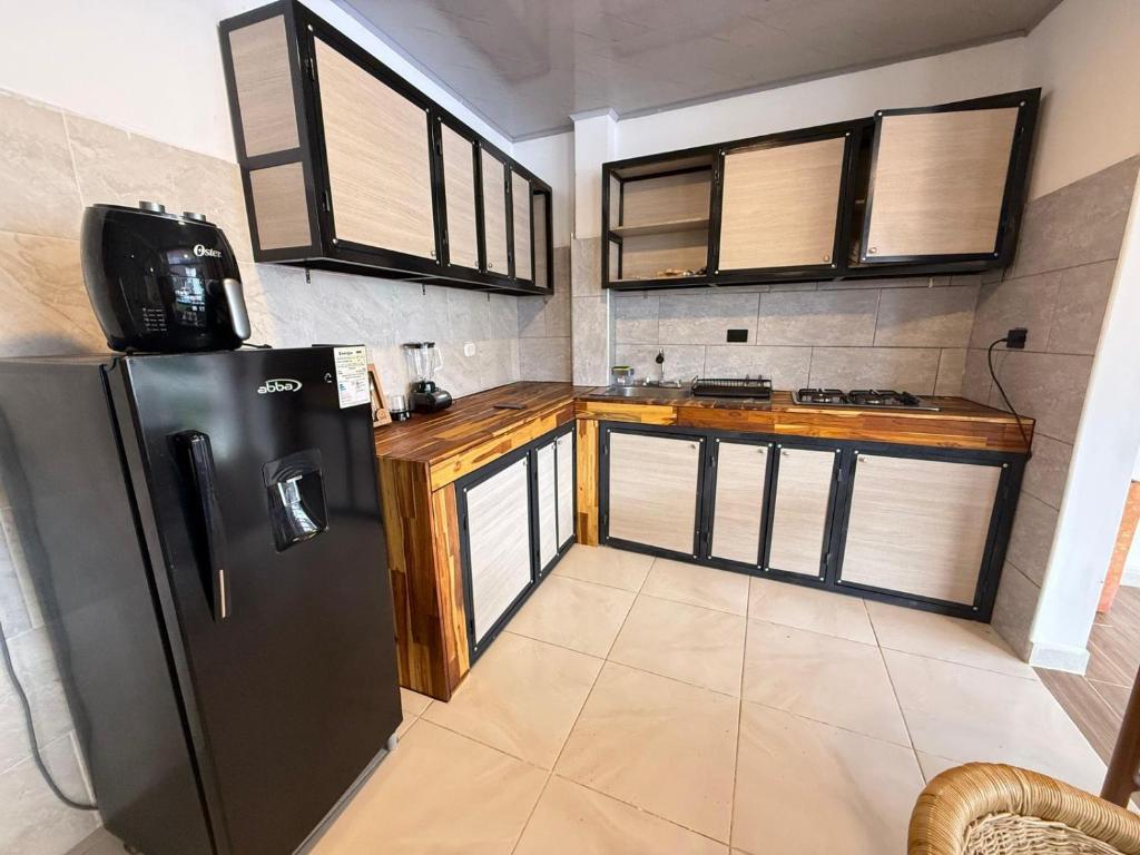 eine Küche mit einem schwarzen Kühlschrank und einigen Fenstern in der Unterkunft Toba hotel in Ibagué