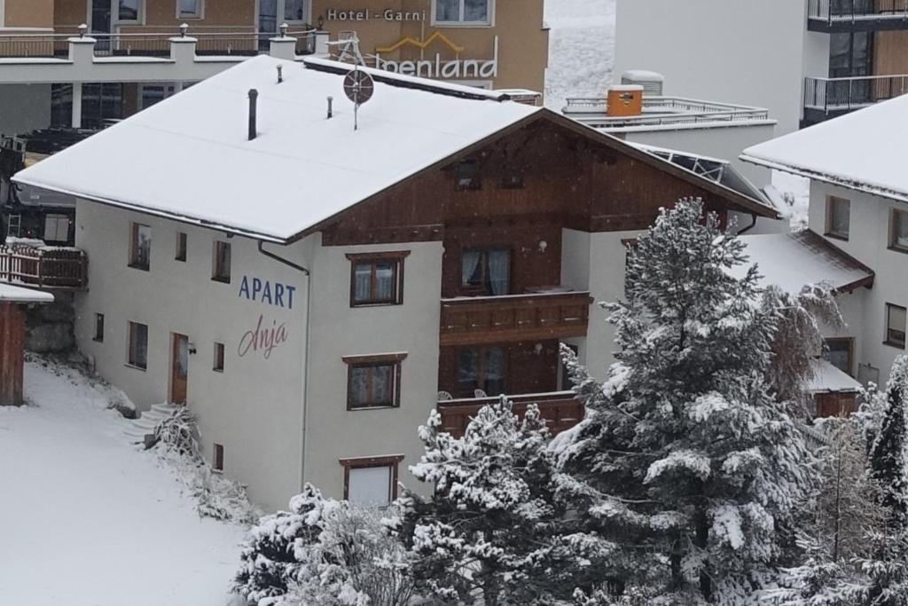 a building covered in snow with trees in front of it at Apart Anja in Ischgl