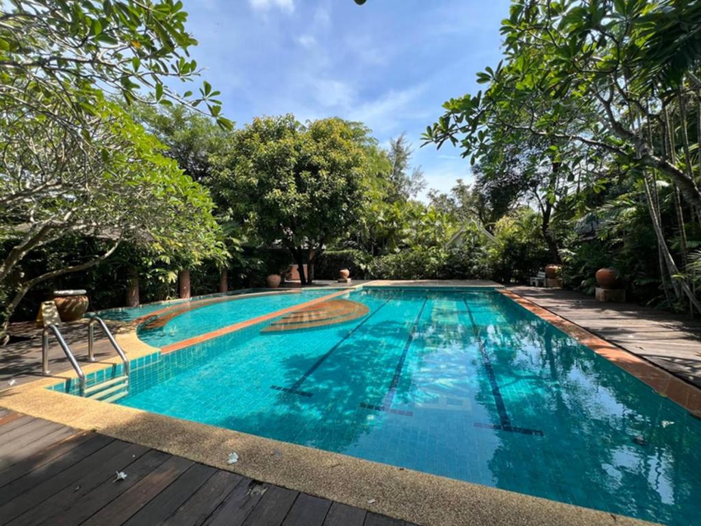 a swimming pool with blue water and trees in the background at Rainbow Arokaya Welness Resort in Ban Hua Sai