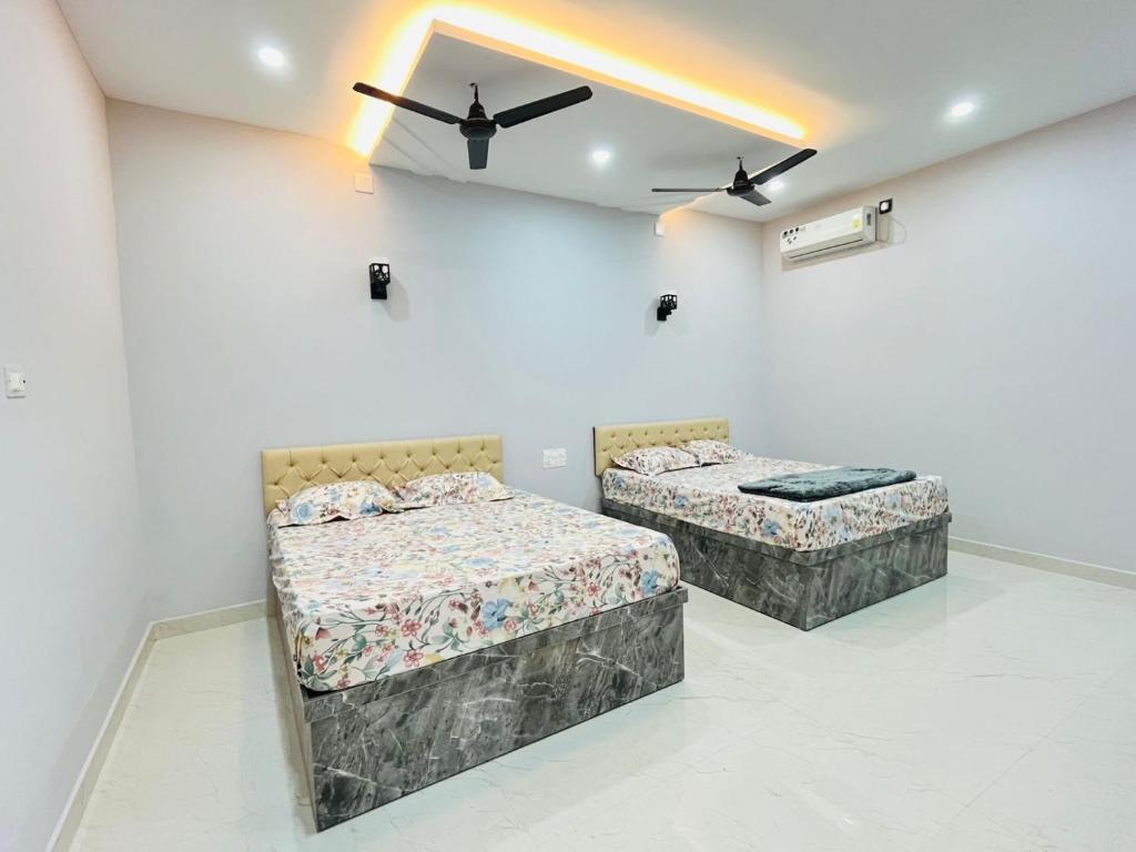 two beds in a room with a ceiling fan at Suits by lowtide in Udupi