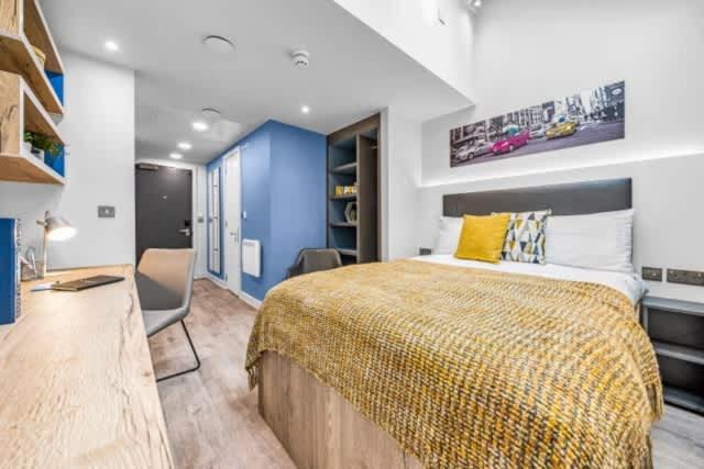 a bedroom with a large bed with a yellow blanket at Practical Studios In Lincoln with Free Grab&Go Breakfast in Lincoln
