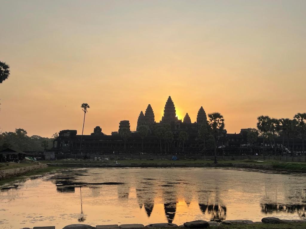 a view of a temple at sunset with a pond at Angkor Nature Voyages in Phumi Ta Phul