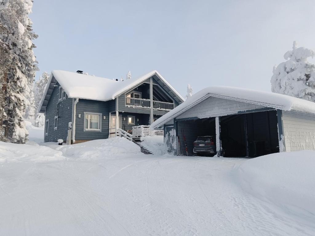 a house covered in snow next to a garage at Villa Ilves A in Syöte