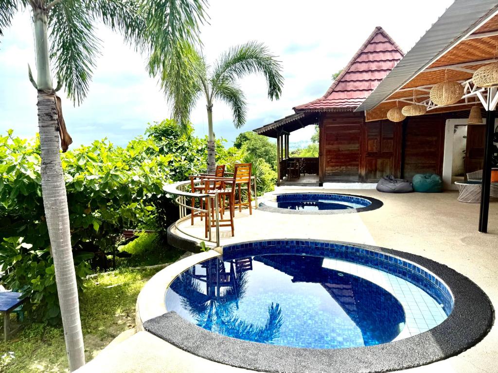 a pool in a backyard with a table and chairs at Villa Bakso Mentigi in Teluknarat