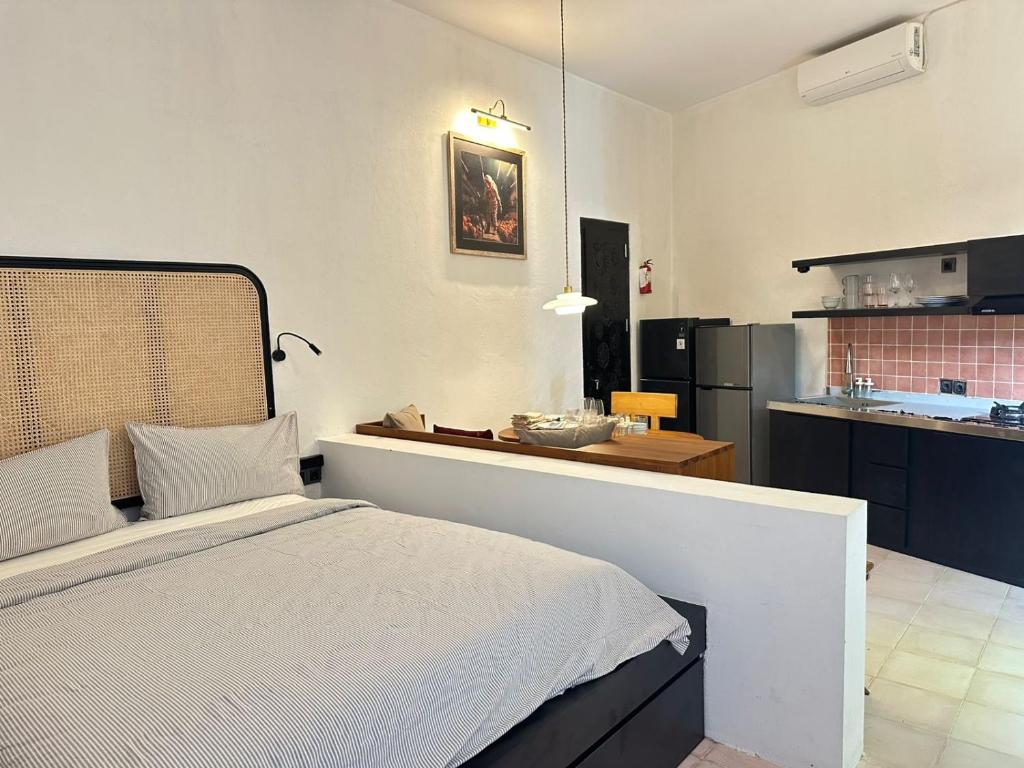 a bedroom with a white bed and a kitchen at Seseh Studio in Cemagi