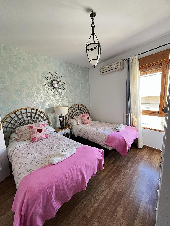 two beds in a room with pink sheets at The Llanete Collection 02 in Martos