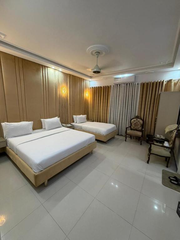 a hotel room with two beds and a chair at Comfort Lodge in Karachi