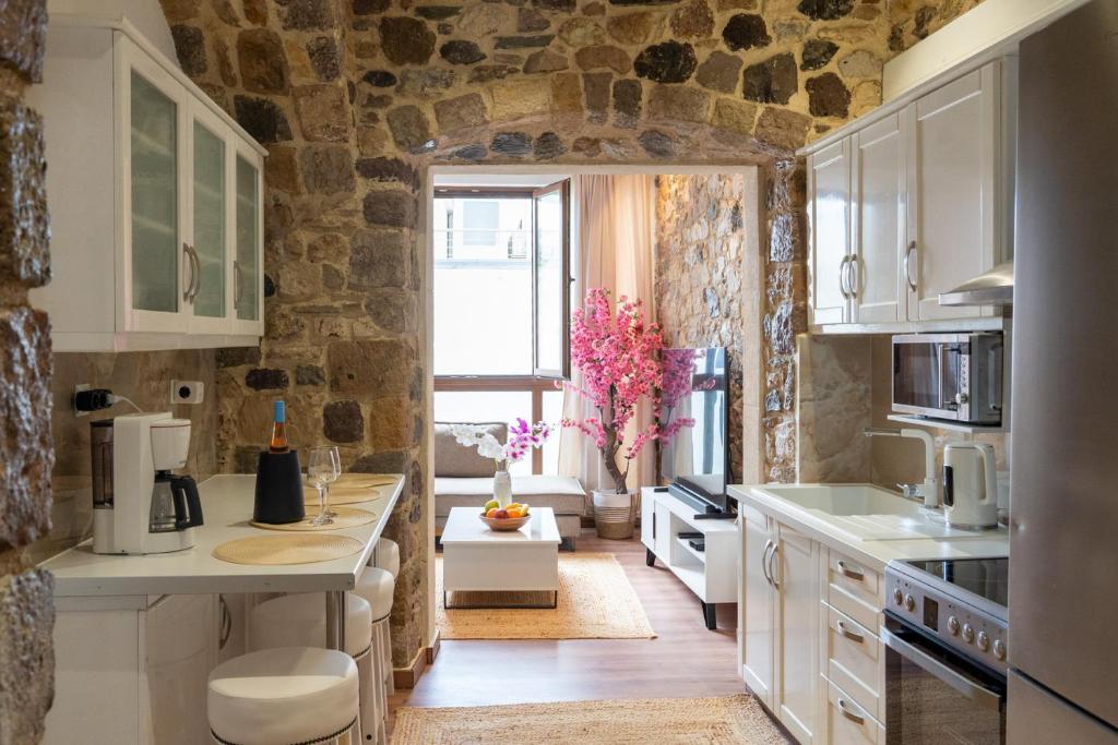 a kitchen with white cabinets and a stone wall at Kos View City , Luxury Old Town in Kos