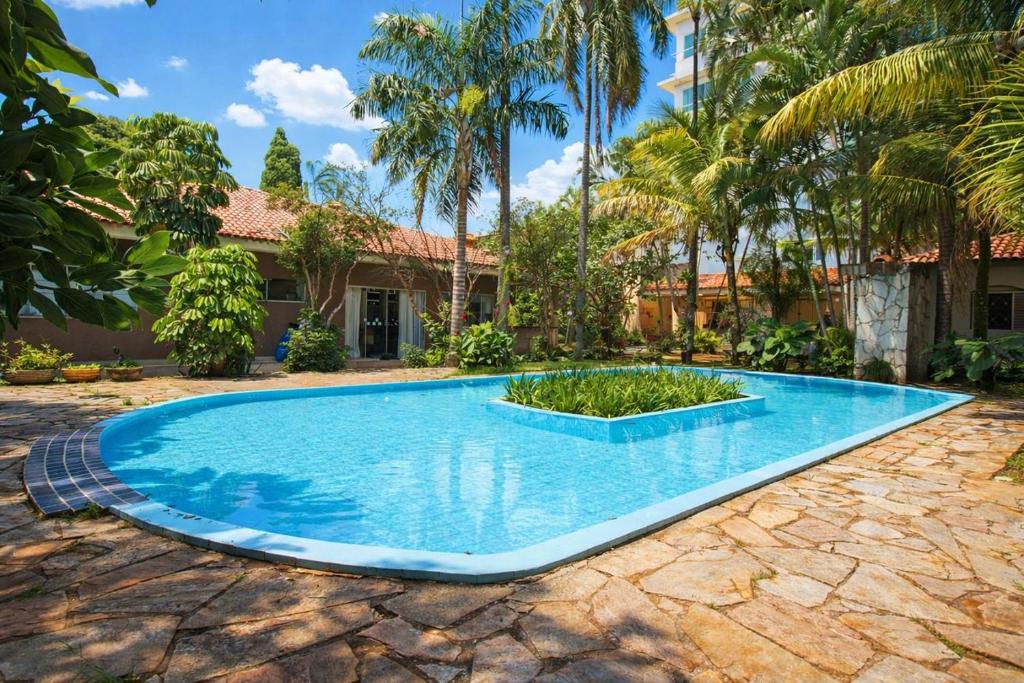 a swimming pool in front of a house with palm trees at Casa com Piscina e Churrasqueira em Taguatinga in Taguatinga