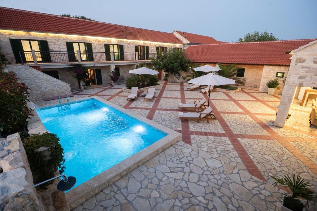 an outdoor swimming pool with umbrellas and a building at Villa Dvori Jokic in Islam Grčki