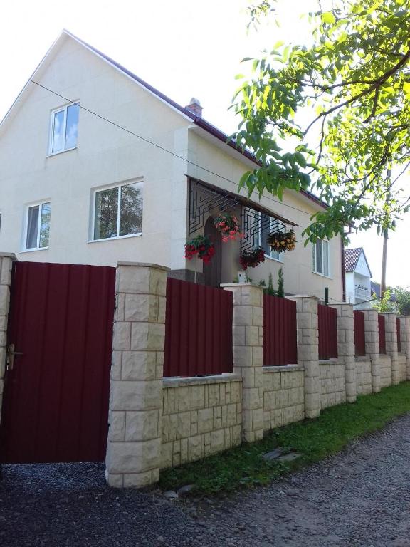 a white house with a fence and a red gate at Садиба Villa Bella in Velyatyn
