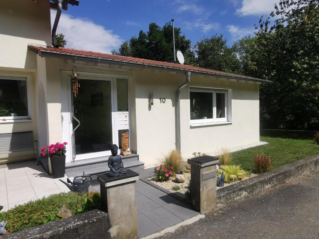 a small white house with a statue in front of it at Ferienwohnung Im Auricher Tal in Vaihingen an der Enz