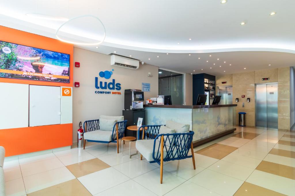 a lobby of a ups store with chairs and a counter at Luds Comfort Hotel in Ponta Grossa