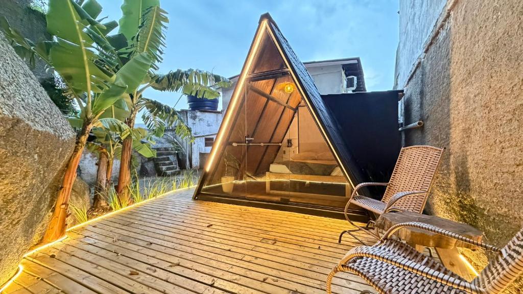 a tiny house on a deck with two chairs at Cabana no Morro do Macaco in Bombinhas
