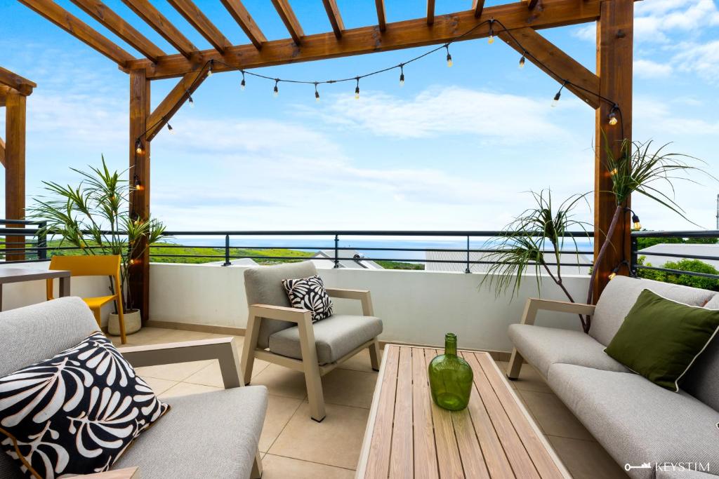 a patio with chairs and a table and a view of the ocean at Koté La Savan' in Saint-Paul