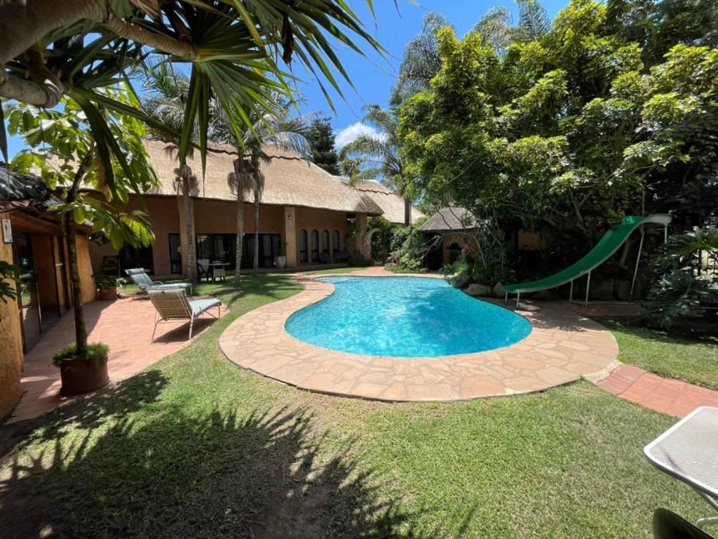 a swimming pool in a yard with a slide at Green Oasis Lodges in Harare