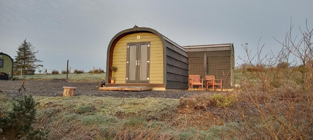 a small shed with a table and a chair in a field at Stag's View in Ballina