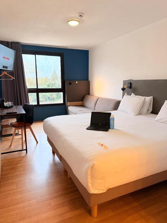 a hotel room with a bed with a laptop on it at Kyriad Blois Sud - Vineuil in Vineuil