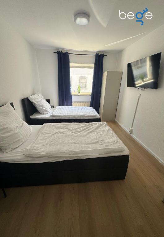 two beds in a small room with a window at BEGE APARTMENTS BalanceBase in Philippsburg