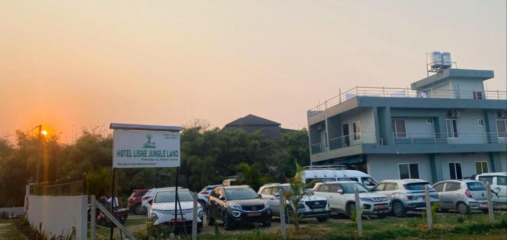 a parking lot with cars parked in front of a building at Hotel Lisne jungle land in Bharatpur